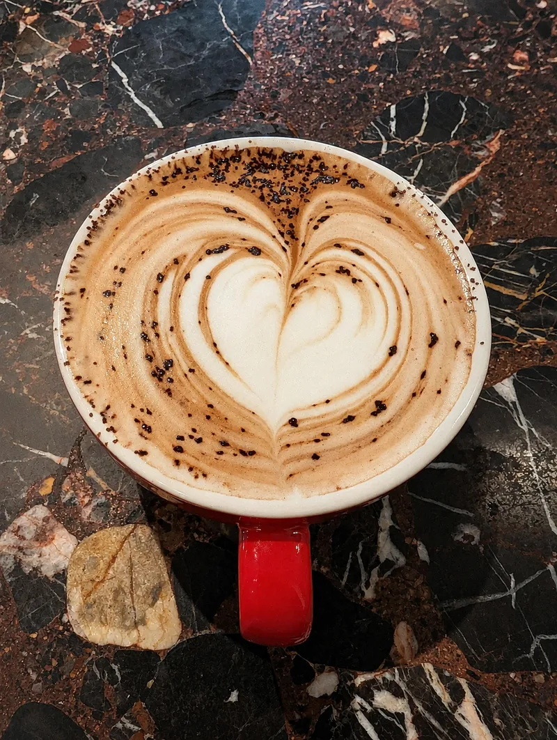 A red coffee cup with heart-shaped latte art