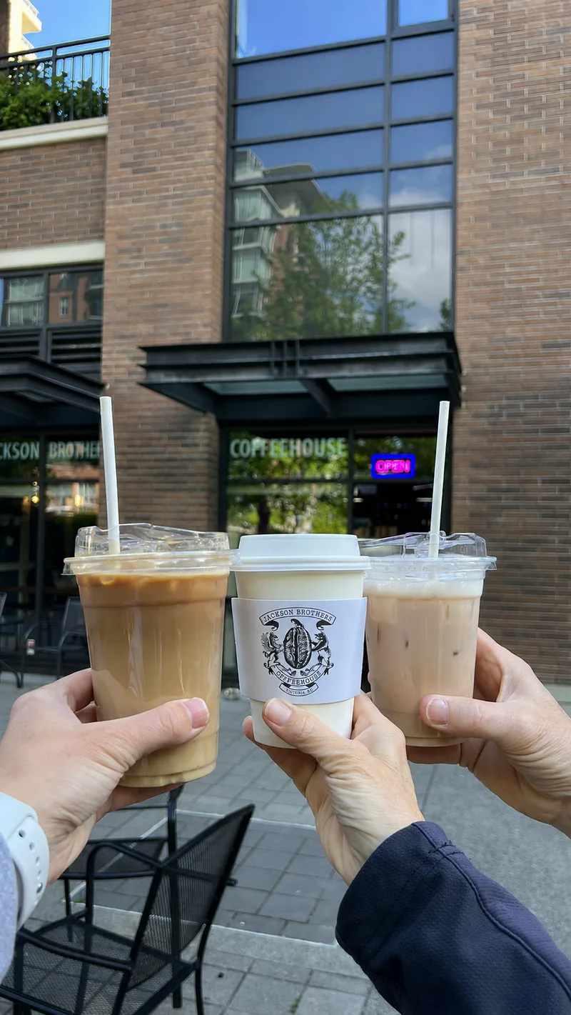 Three takeaway coffees raised outside Jackson Brothers Coffeehouse