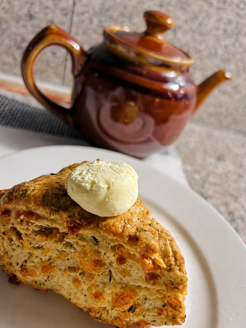 Scone with butter and a brown teapot
