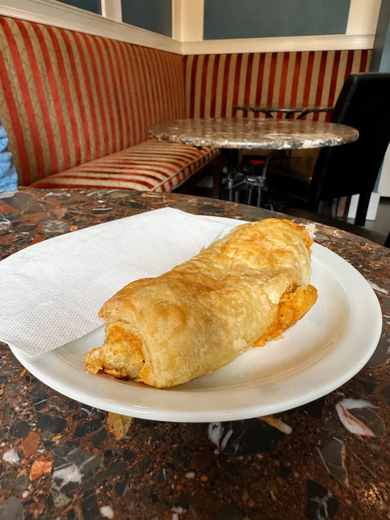 Golden pastry roll on a plate beside the striped seating