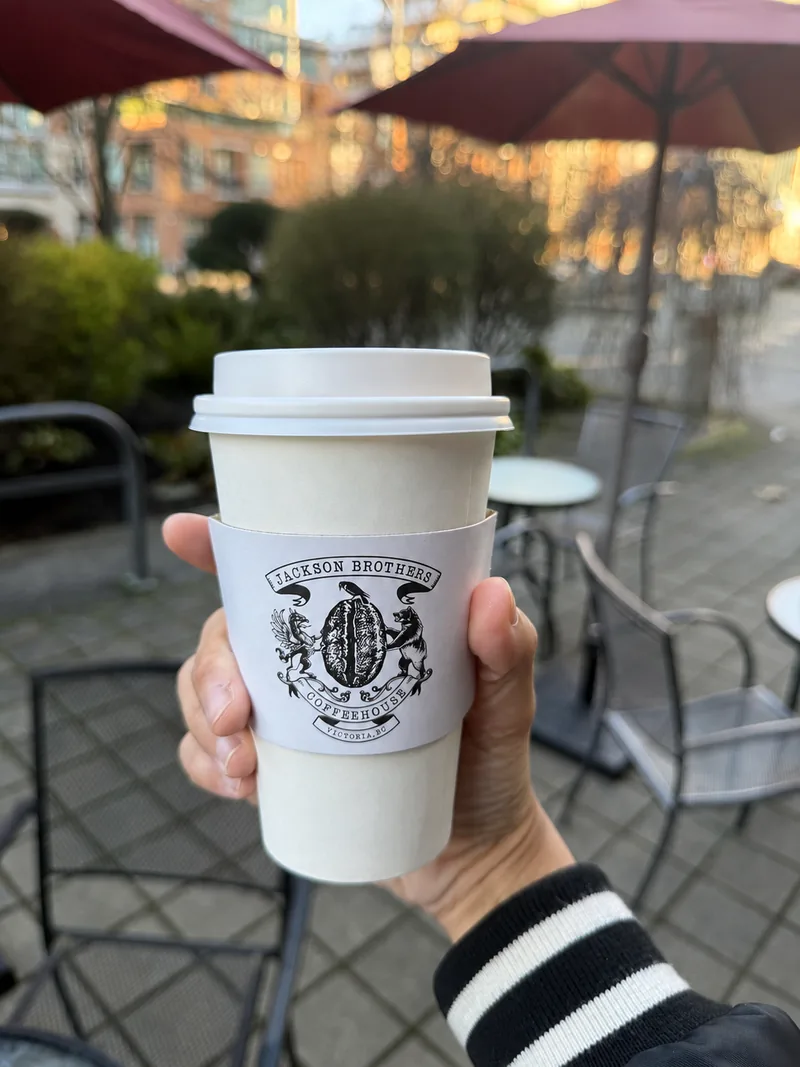 A Jackson Brothers takeaway cup held on the café patio
